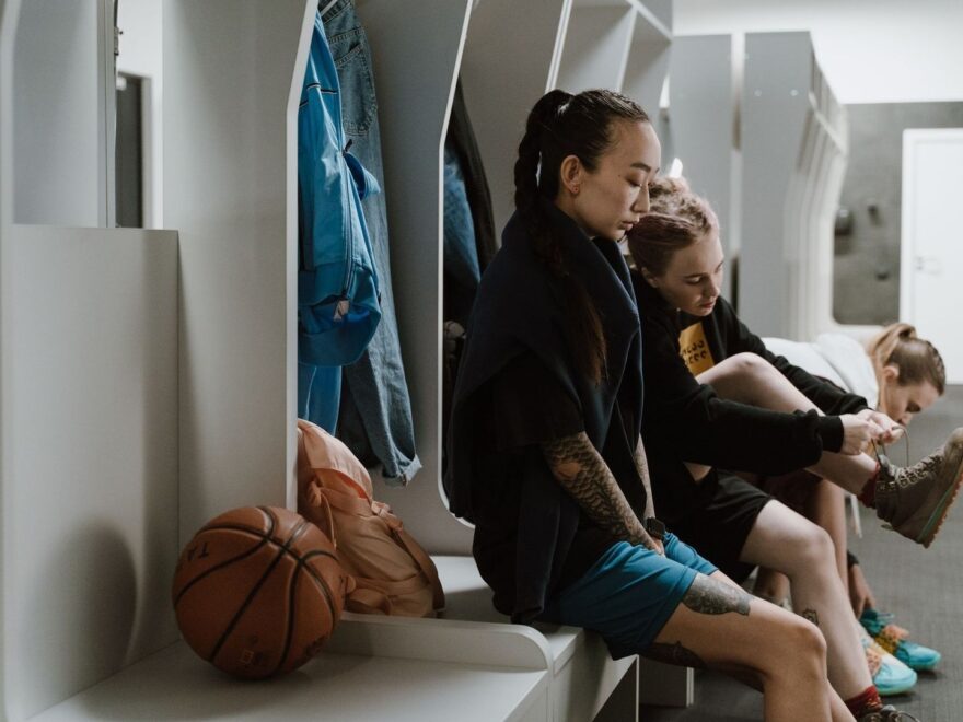 Unga spelare sitter tillsammans i ett omklädningsrum med en basketboll